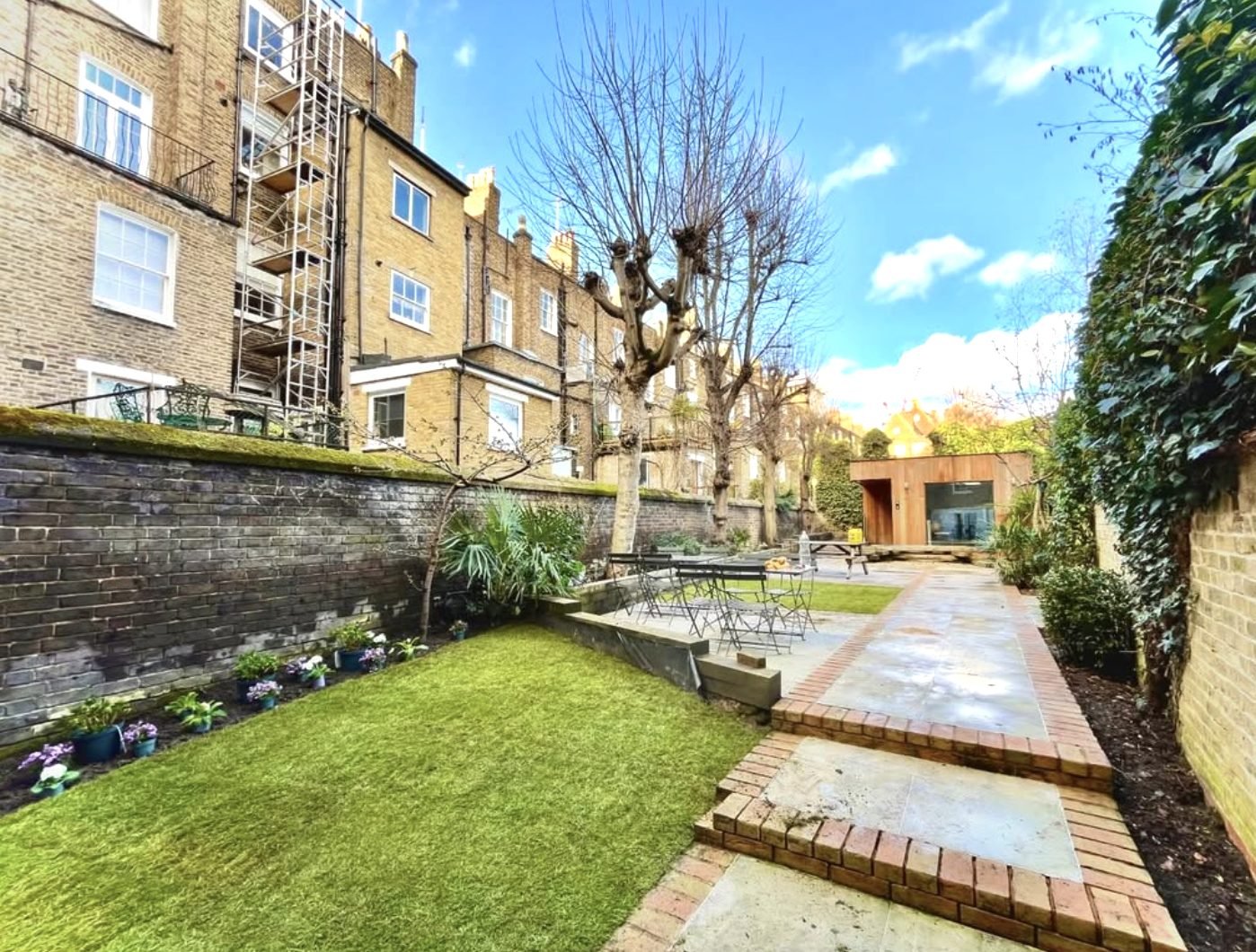 Brick-edged paving path, steps and lawn leading to a garden room